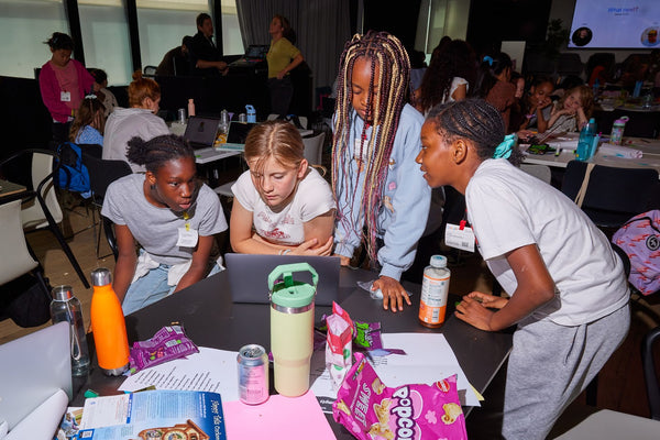 Children gathered around a table with snacks and drinks in a entrepreneurship workshop setting
